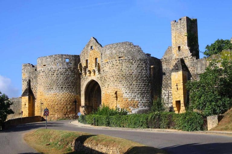Château médiéval en pierre avec tours et entrée.